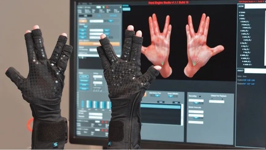 图片显示双手戴着黑色手套，手套上布满传感器，背景是显示手部3D模型的电脑屏幕。